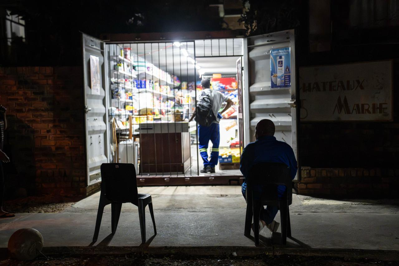The After-Hours Shop:  A view of a street-side stall at night, with a brightly lit interior illuminating the goods on display. 