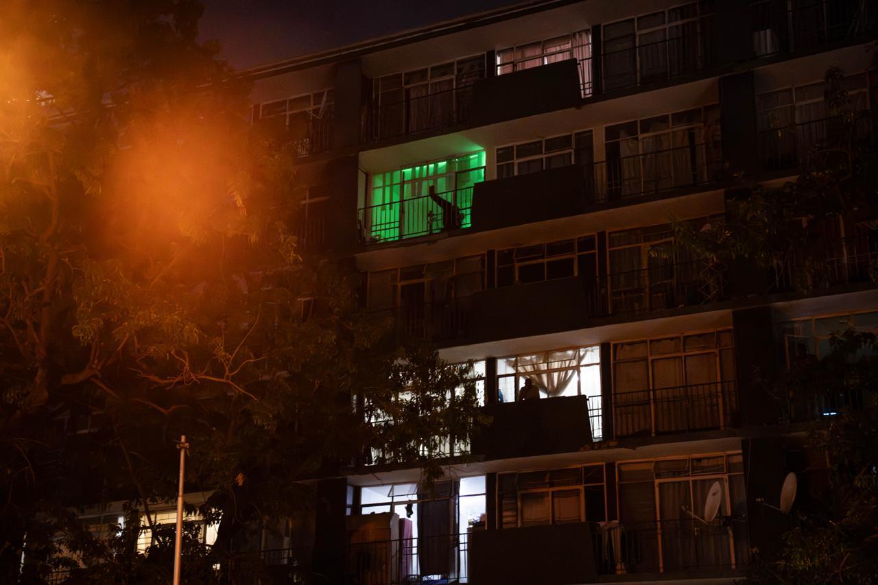 Green Glow: Balcony at Night A vivid green neon light casts an intriguing glow from an apartment balcony, standing out against the dark, quiet facade of the residential block.