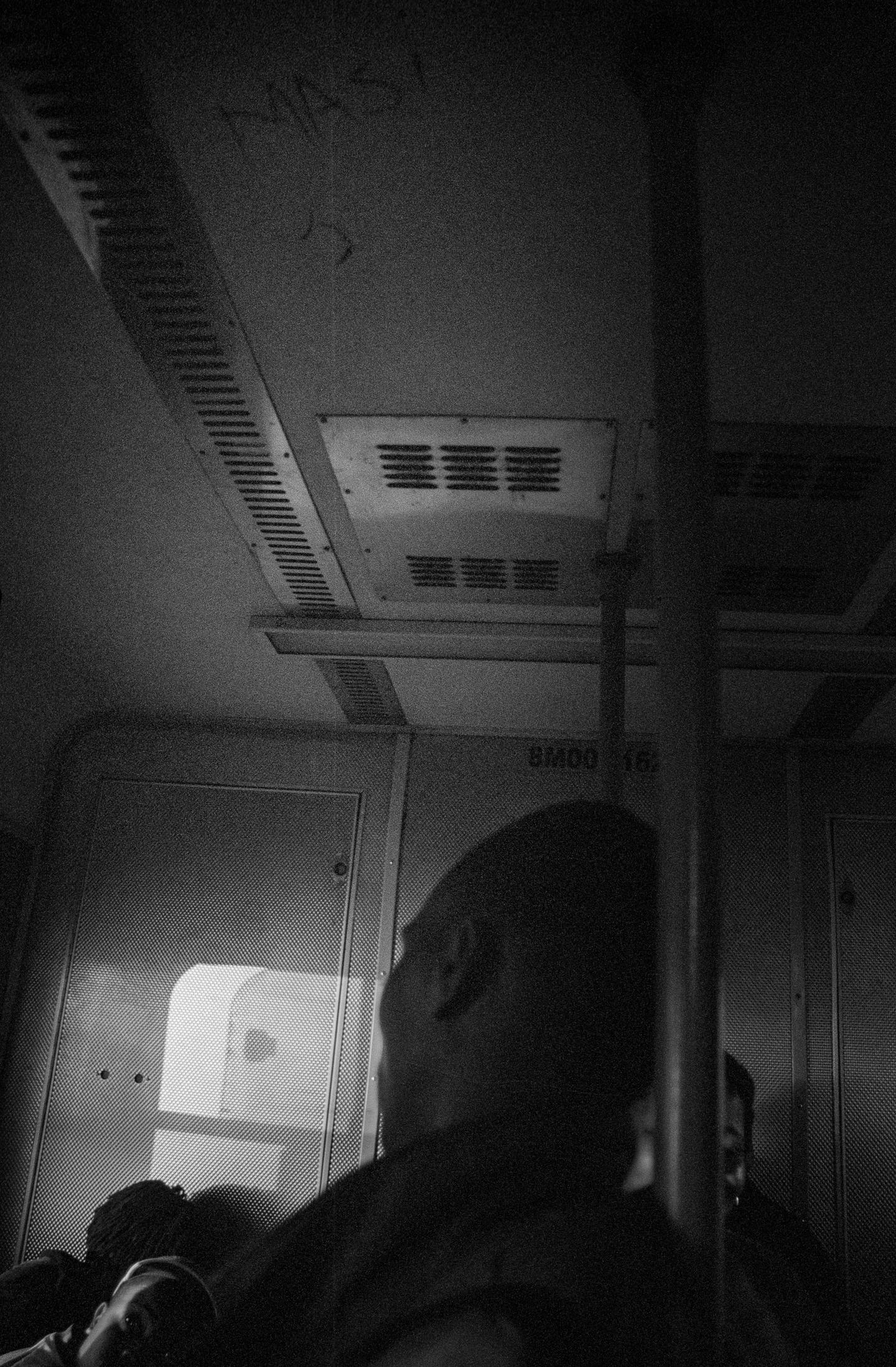 The interior ceiling of a train carriage, with a passenger in silhouette below.