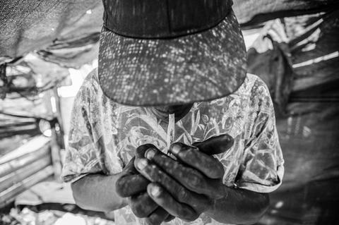 Black and white close view of hands working over patterned cloth.