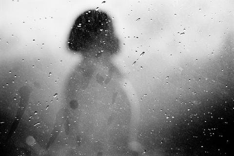 Person's blurred silhouette seen through steamed glass covered in water droplets, Cape Town.